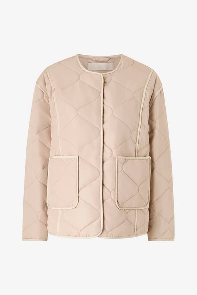 Beige tikattu takki, jossa on kaksi etutaskua.