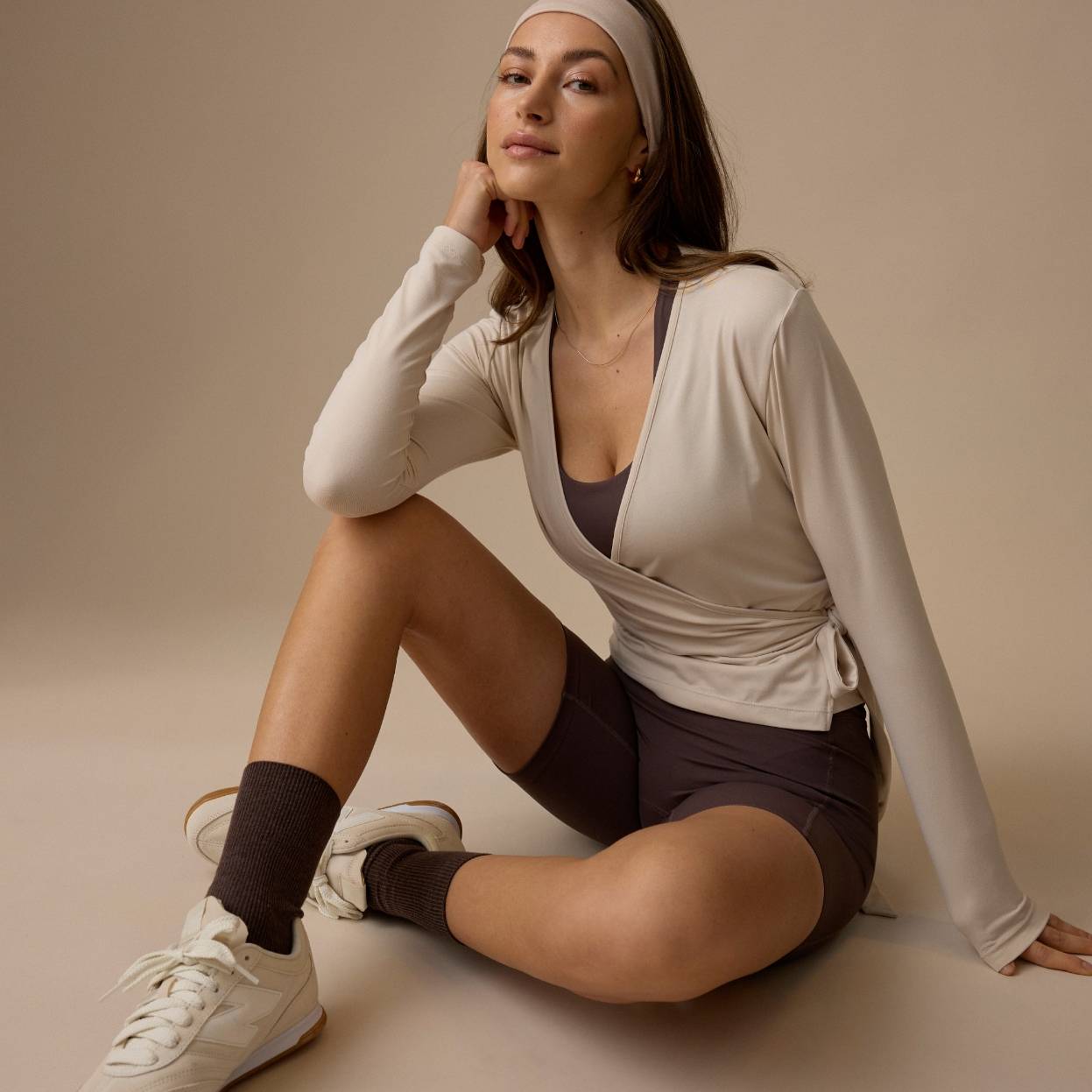 Kvinne i sporty antrekk med sneakers i studiomiljø.