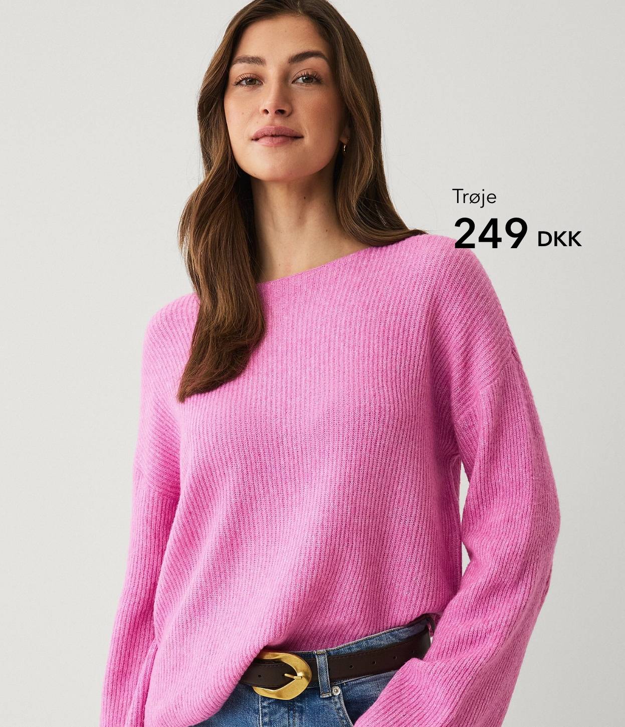 Kvinde i pink striktrøje mod lys baggrund.