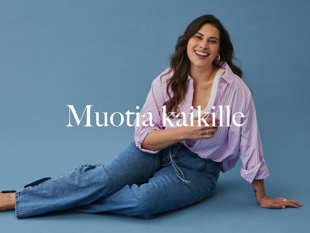 Nainen raidallisessa paidassa ja farkuissa sinistä taustaa vasten.