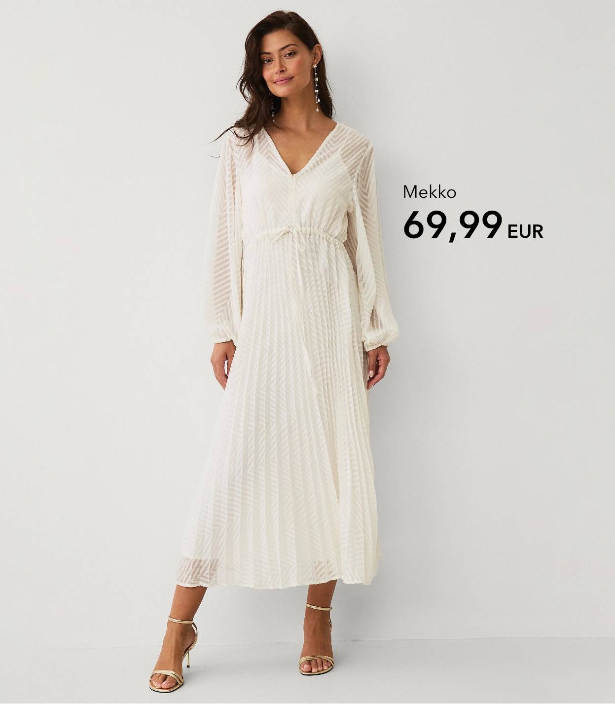 Nainen pitkässä vaaleassa mekossa, jossa on tekstuuria ja vyötärönauha.